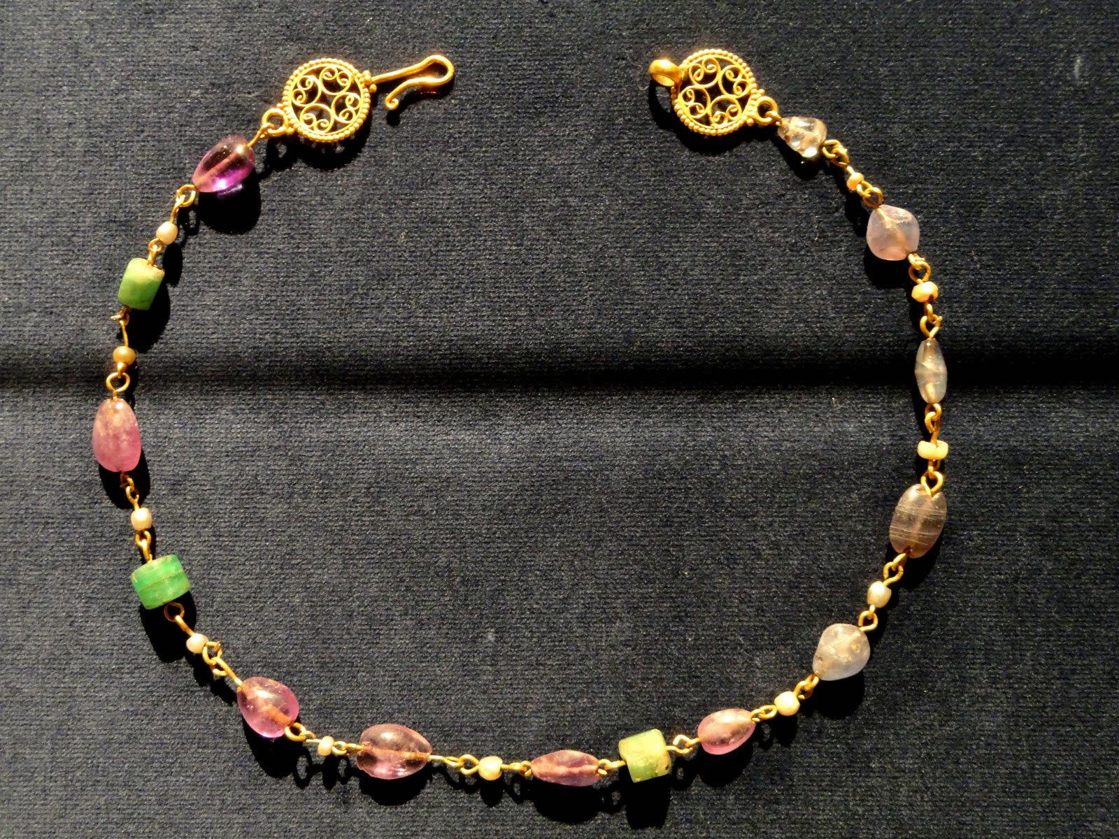 Horizontal display of an Early Byzantine gold necklace with amethyst, sapphire, feldspar and pearls from the 500s AD