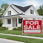 For sale sign in front of a suburban house as US home sellers cut prices