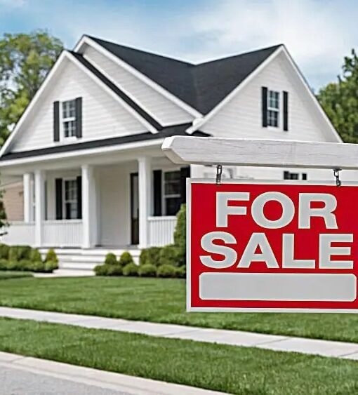 For sale sign in front of a suburban house as US home sellers cut prices