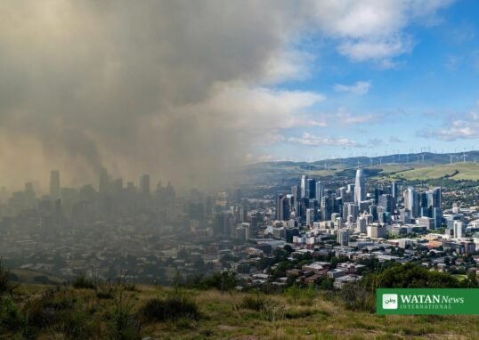 A city skyline split between polluted air and clean blue sky