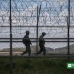 North Korean soldiers patrol along barbed wire fence at DMZ border