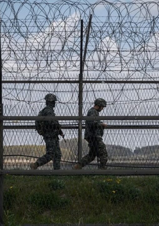 North Korean soldiers patrol along barbed wire fence at DMZ border