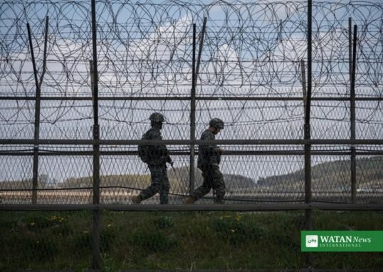 North Korean soldiers patrol along barbed wire fence at DMZ border
