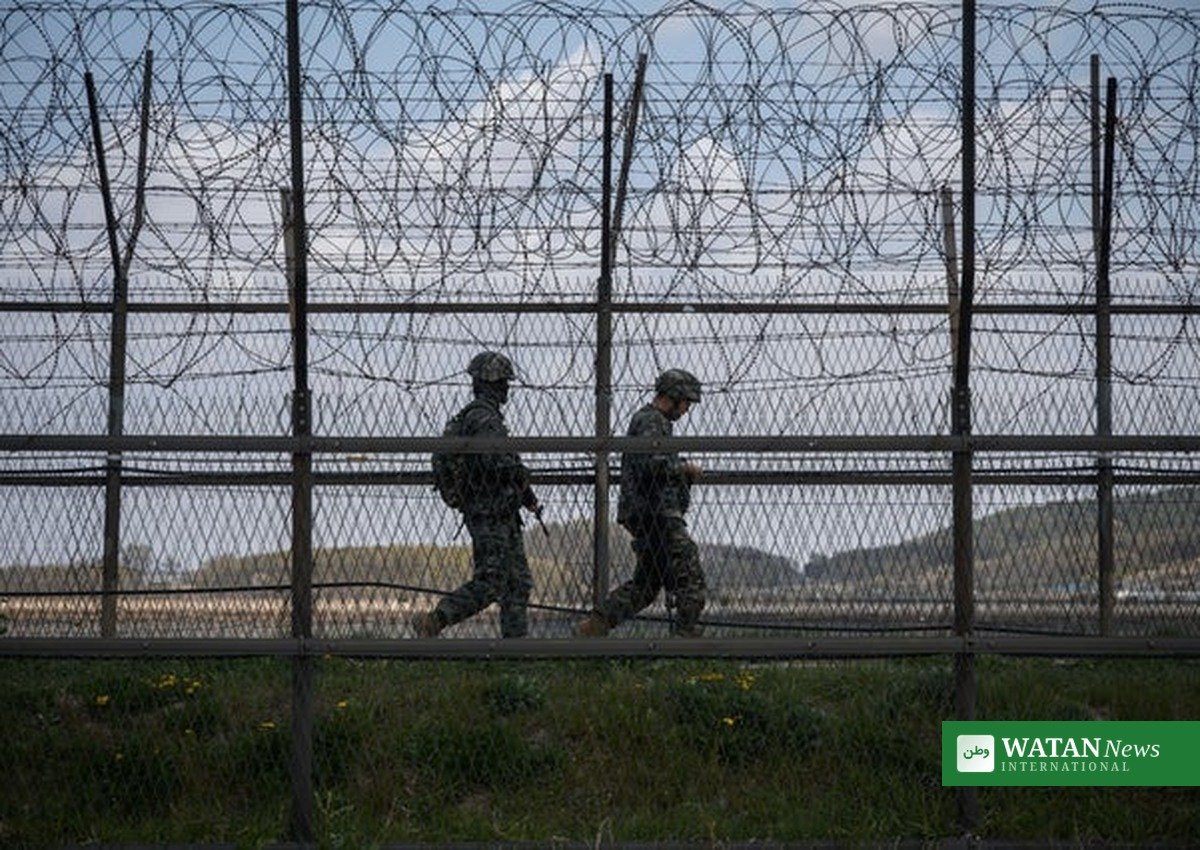 North Korean soldiers patrol along barbed wire fence at DMZ border