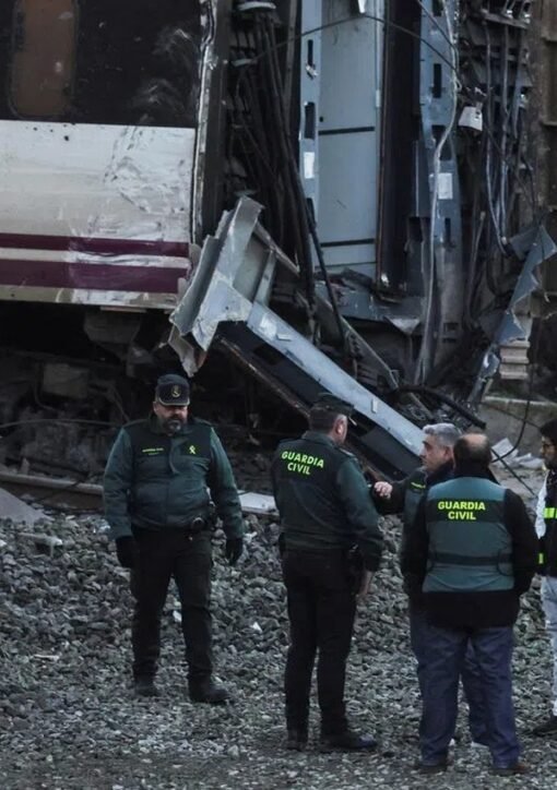 Investigators and Guardia Civil officers examine wrecked Renfe carriages at the Spanish rail crash site
