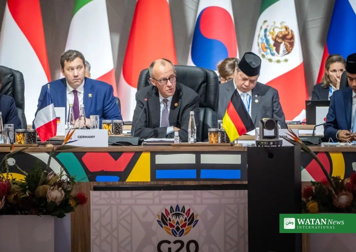 Delegates seated at a G20 summit table with national flags behind them