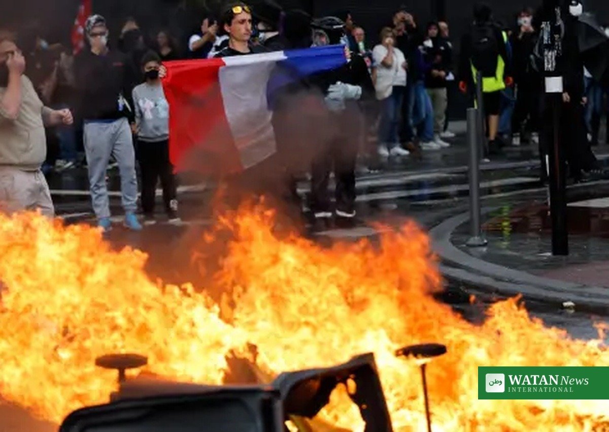 French protester with a national flag near a burning barricade during the France riots of October 2026