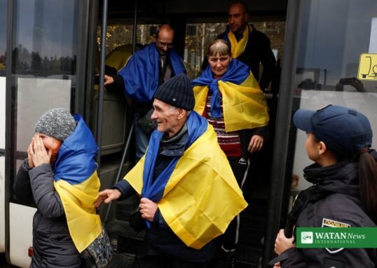 Oleshky evacuees draped in Ukrainian flags disembarking a bus on arrival in Ukraine