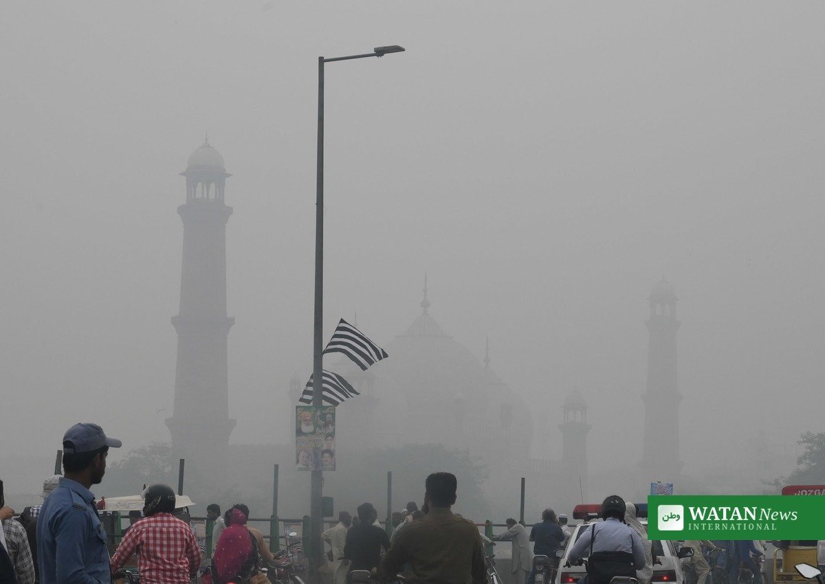 لاہور اسموگ میں بادشاہی مسجد کے مینار اور سڑک پر شہری