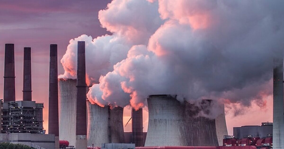 Coal-fired power plant with cooling towers under a hazy sky, illustrating the EPA's proposed repeal of power plant emissions standards
