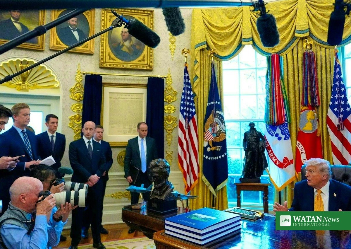 Donald Trump at the Resolute desk in the Oval Office with reporters during a press briefing