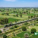 سبز کھیتوں کے درمیان پٹری پر چلتی مسافر ٹرین